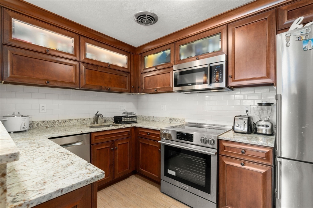 31 Warren Street, Unit B1 Waltham, MA 02453 - Photo 8 of 22 a kitchen with stainless steel appliances granite countertop a stove and a microwave
