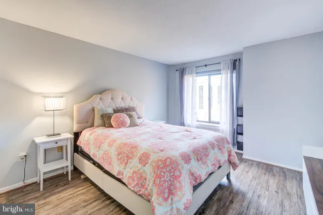 a large bed sitting in a bedroom next to a window and a wooden floor