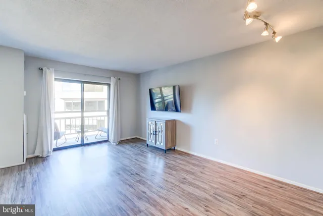 a view of an empty room with a window and wooden floor
