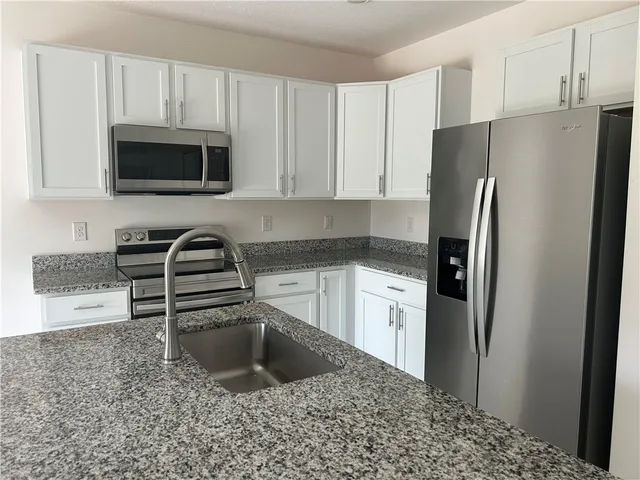 a kitchen with stainless steel appliances granite countertop a refrigerator stove and microwave