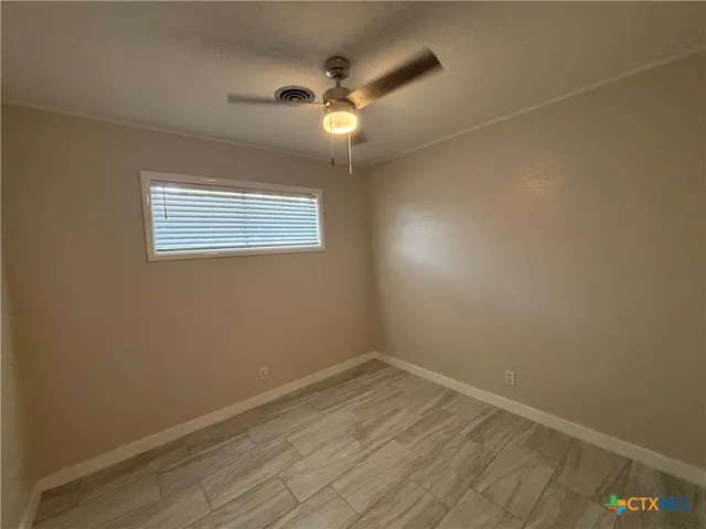 an empty room with a ceiling fan and window