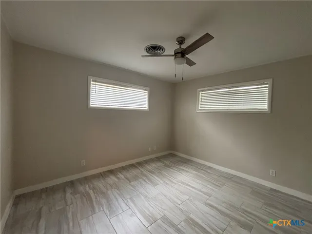 a view of an empty room with wooden floor and a window