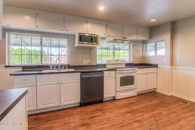 a white kitchen with granite countertop a stove top oven sink and cabinets