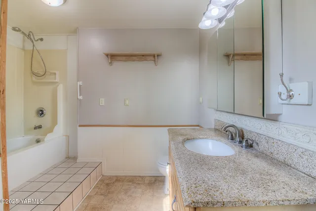 a bathroom with a granite countertop sink a mirror and a bathtub