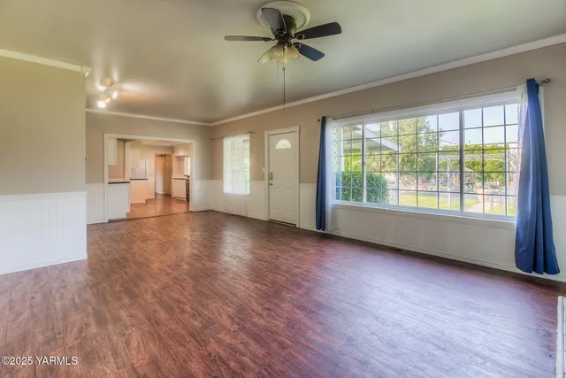 a view of a livingroom with wooden floor a ceiling fan and windows