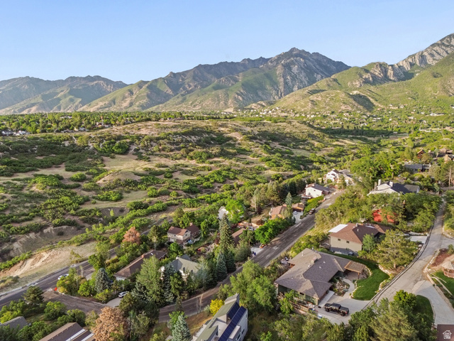 2342 Charros Road Sandy, UT 84092 - Photo 79 of 94 Expansive aerial perspective showcasing a mountainous backdrop, verdant hillside terrain, and a residential street with multiple homes