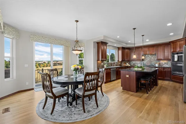 a kitchen with stainless steel appliances kitchen island granite countertop a table chairs and a living room