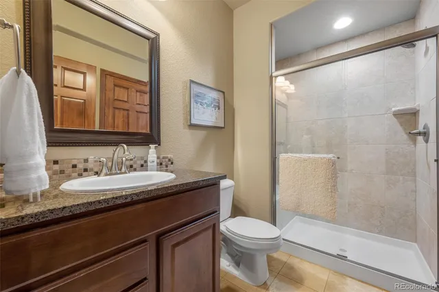 a bathroom with a granite countertop sink a toilet a mirror and shower