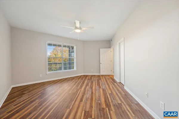 a view of an empty room with wooden floor and a window