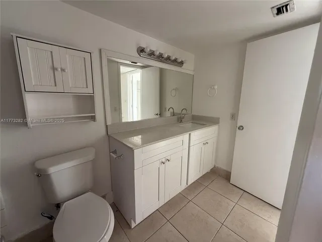 a bathroom with a granite countertop sink mirror vanity and toilet