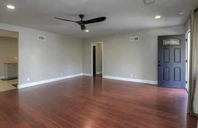 a view of a livingroom with wooden floor and a ceiling fan