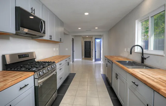 a kitchen with stainless steel appliances granite countertop a stove a sink and a microwave