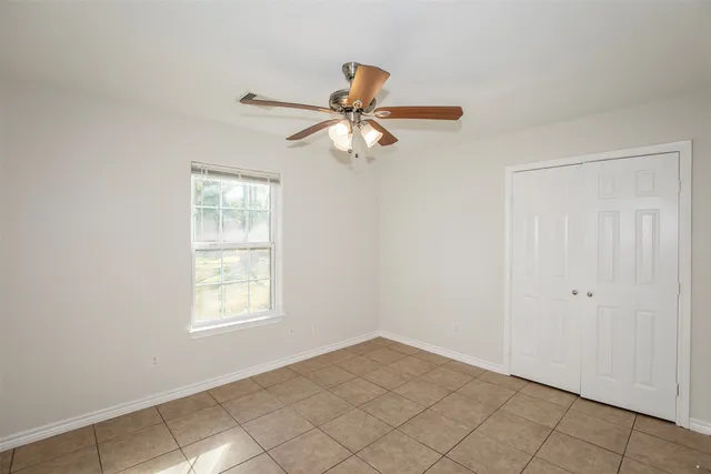 an empty room with windows and fan