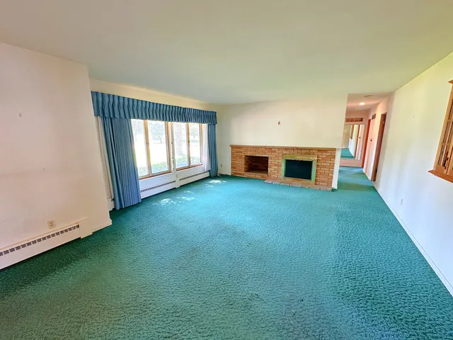 a view of an empty room with window and fireplace