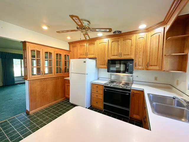 a kitchen with stainless steel appliances granite countertop a refrigerator a stove and a sink with wooden cabinets