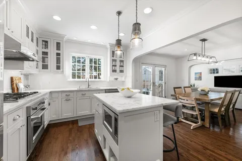 a kitchen with a stove a sink dishwasher a dining table and chairs with wooden floor
