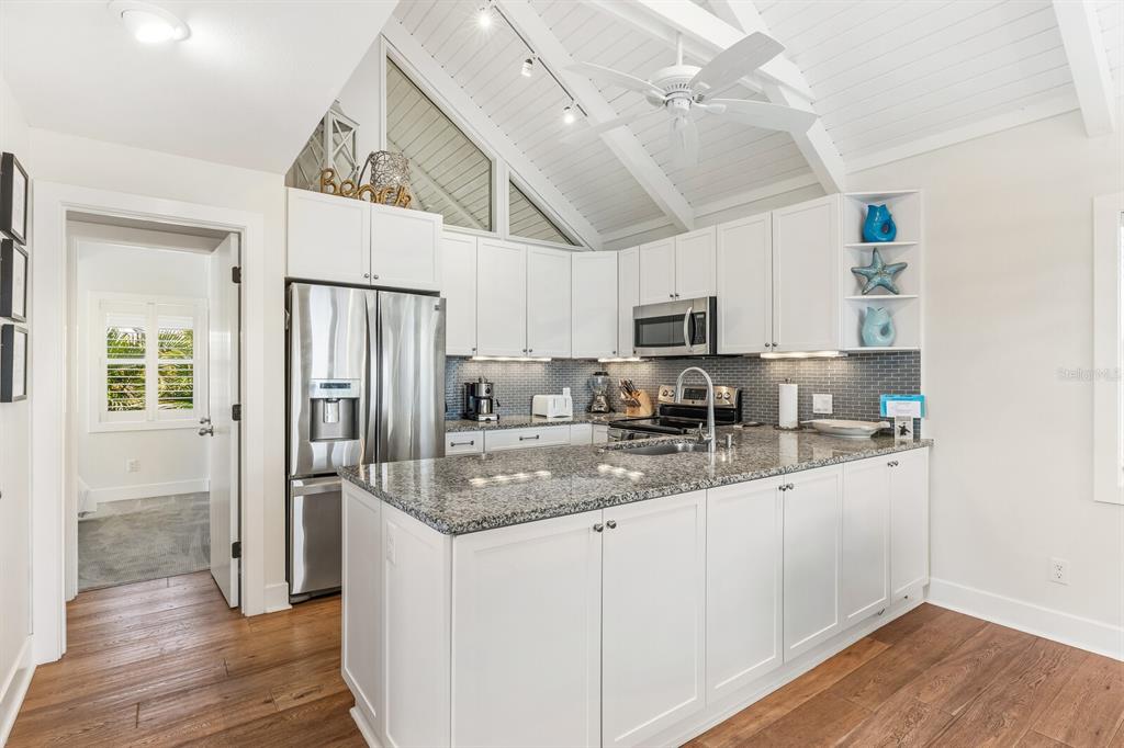 5000 Gasparilla Road, Unit 19 Boca Grande, FL 33921 - Photo 6 of 48 a kitchen with stainless steel appliances granite countertop a refrigerator a sink dishwasher a oven with white cabinets and wooden floor