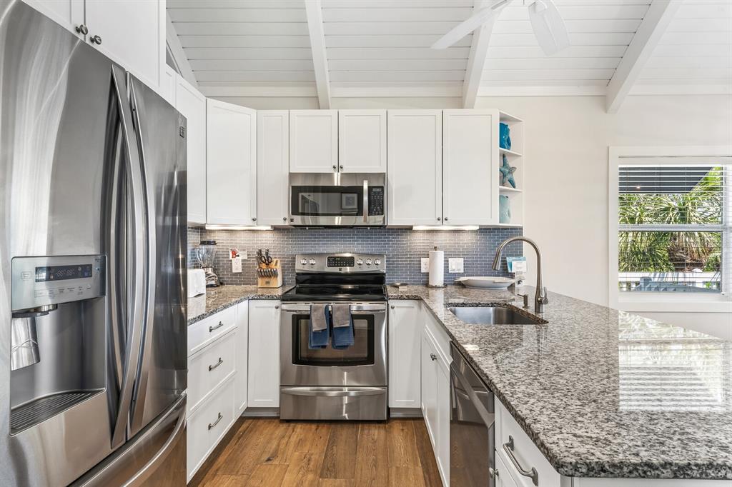 5000 Gasparilla Road, Unit 19 Boca Grande, FL 33921 - Photo 7 of 48 a kitchen with stainless steel appliances granite countertop a stove top oven a refrigerator and a sink