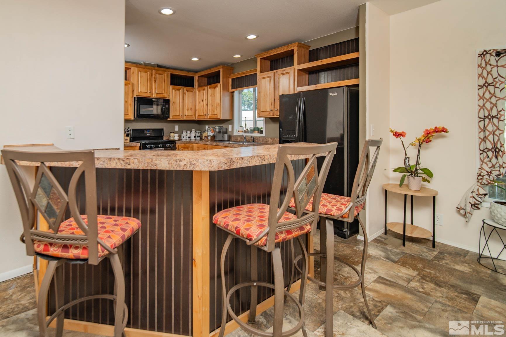 16210 Rhyolite Circle Reno, NV 89521 - Photo 13 of 39 a kitchen with stainless steel appliances a dining table chairs and a refrigerator