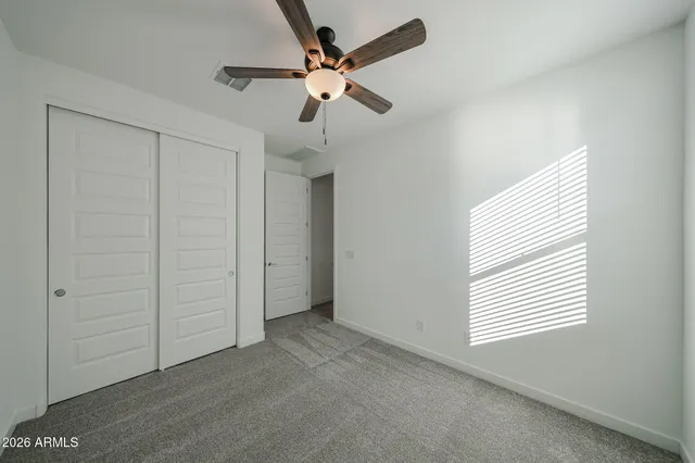 an empty room with a ceiling fan and window