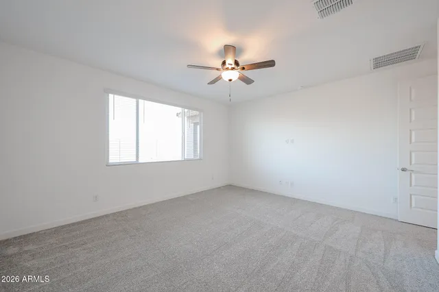 an empty room with windows and fan
