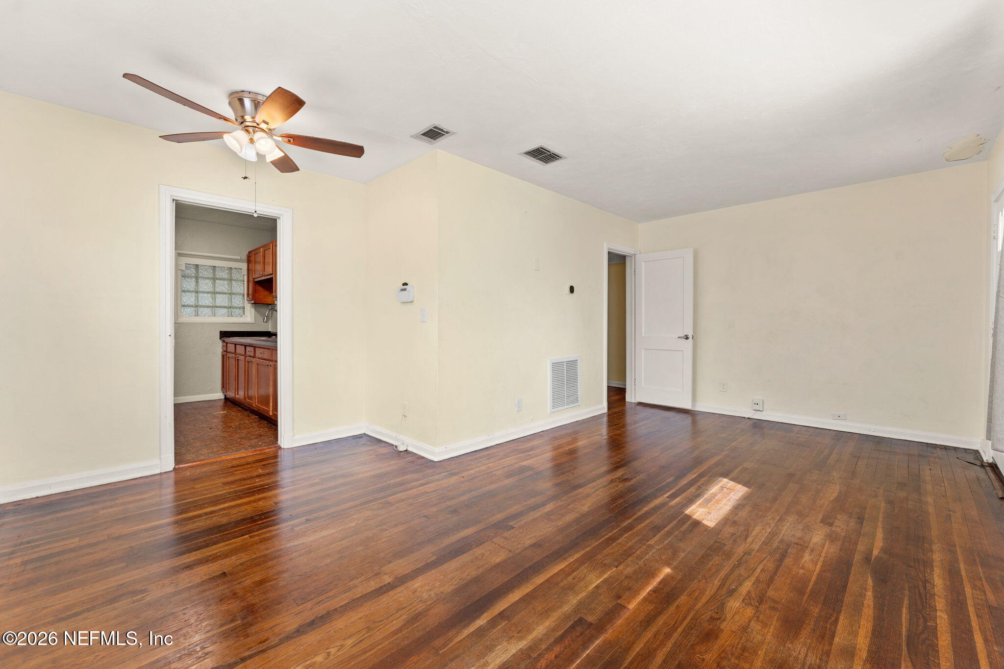 5331 Sharon Terrace Jacksonville, FL 32207 - Photo 3 of 16 an empty room with wooden floor chandelier fan and windows