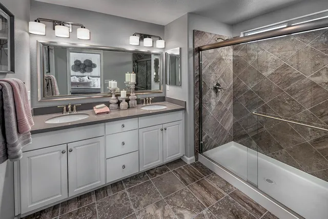 a bathroom with double vanity and a mirror