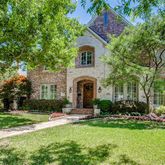 a front view of a house with garden and trees