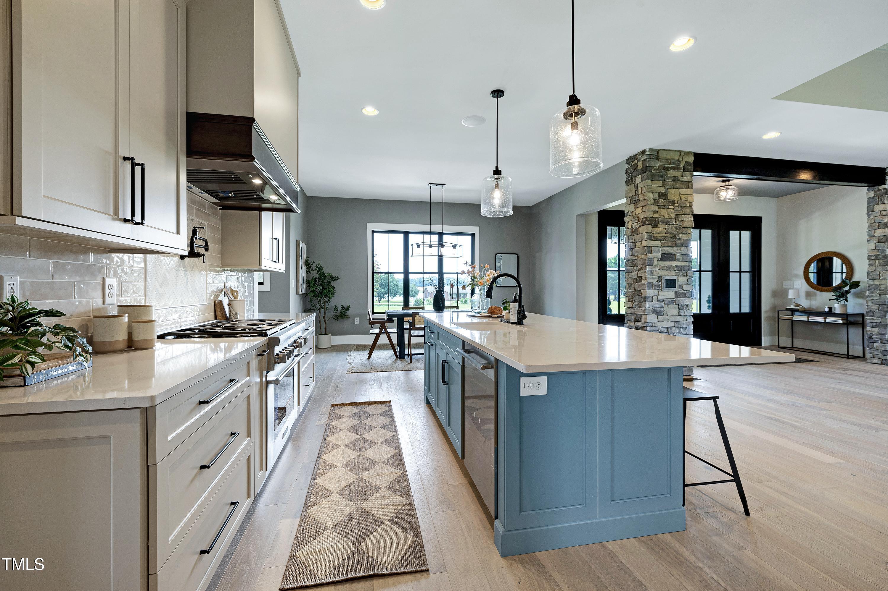 6509 Zebulon Road Wake Forest, NC 27587 - Photo 8 of 100 a large kitchen with stainless steel appliances kitchen island granite countertop a large stove a sink dishwasher and white cabinets with wooden floor