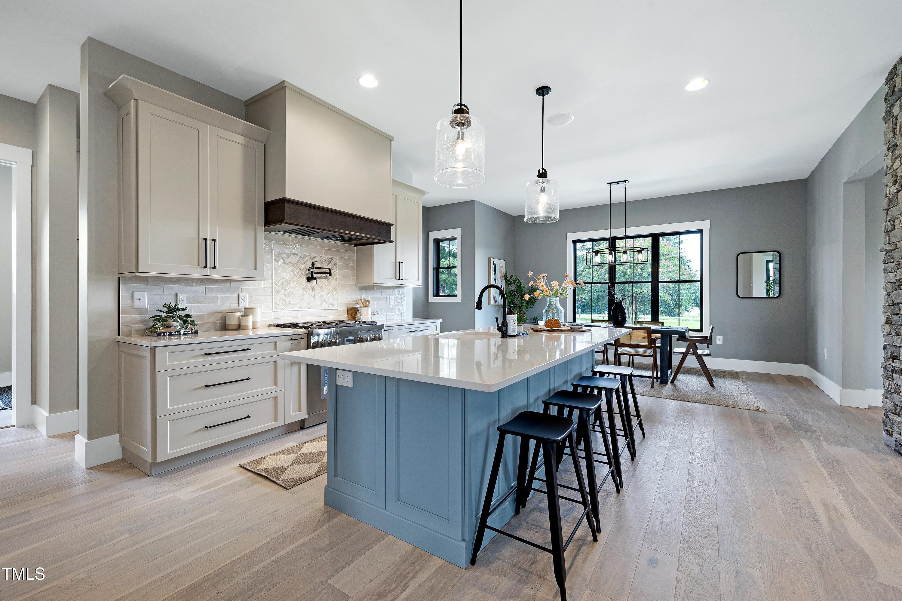 6509 Zebulon Road Wake Forest, NC 27587 - Photo 9 of 100 a kitchen with stainless steel appliances kitchen island granite countertop a table chairs and a refrigerator