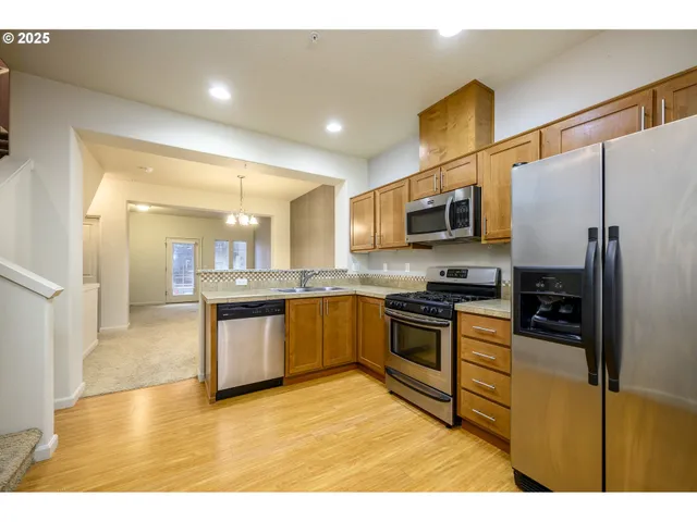 a kitchen with stainless steel appliances granite countertop a refrigerator a stove top oven and a sink