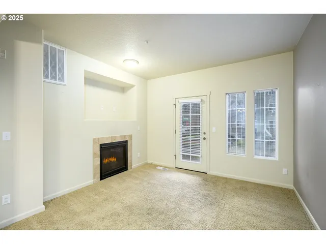 a view of an empty room with a fireplace and window