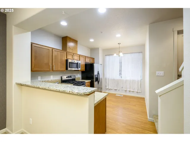 a view of a kitchen with kitchen island granite countertop a sink and cabinets