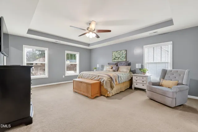 a spacious bedroom with a bed couch and windows