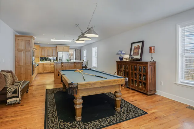 a view of a kitchen with kitchen island stainless steel appliances wooden floor dining table and chairs