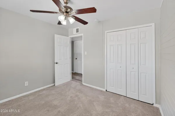 an empty room with closet and a chandelier fan