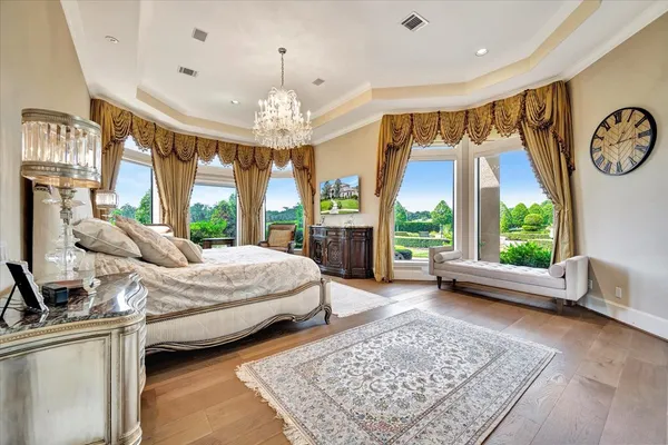 a spacious bedroom with a large bed and a chandelier
