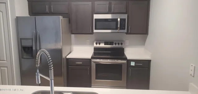 a kitchen with stainless steel appliances granite countertop a refrigerator a stove and a microwave with island