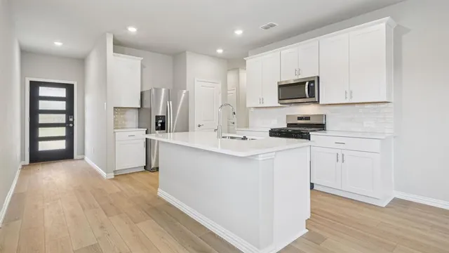 a kitchen with white cabinets and stainless steel appliances