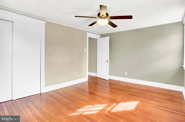 an empty room with wooden floor and ceiling fan