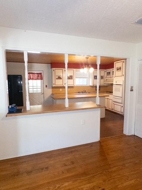 613 Laurel Road Athens, TX 75751 - Photo 7 of 13 Open concept kitchen with wood-finish flooring, white cabinetry, integrated appliances, and a pass-through bar with turned newel posts