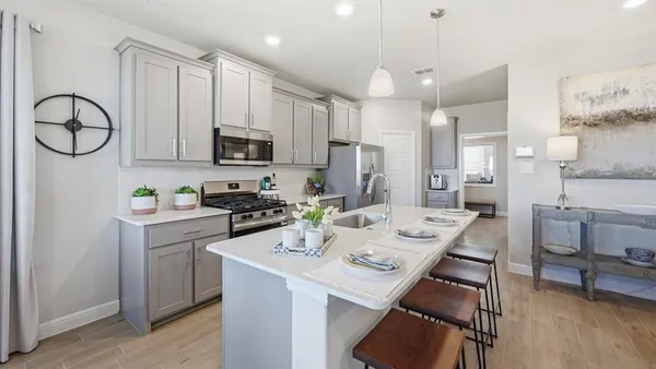 a kitchen with stainless steel appliances kitchen island granite countertop a dining table chairs and a refrigerator