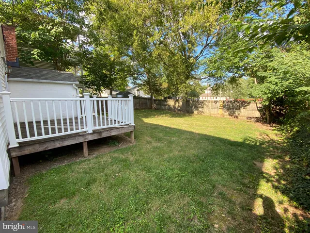 a view of a deck in the backyard with large trees