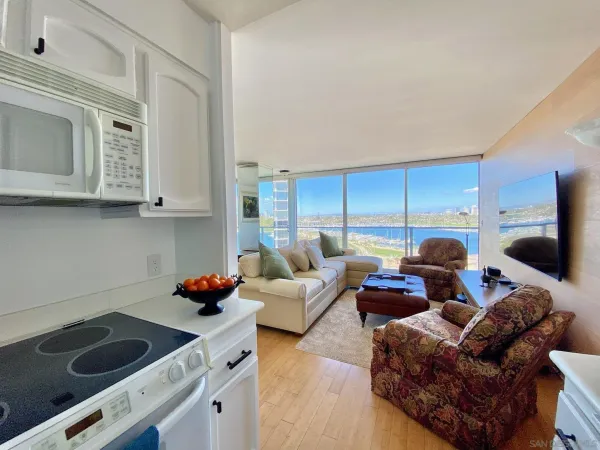 a living room with furniture kitchen view and a window