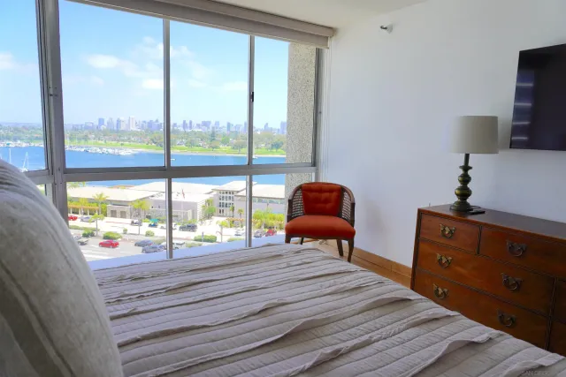 a bedroom with a bed and large windows