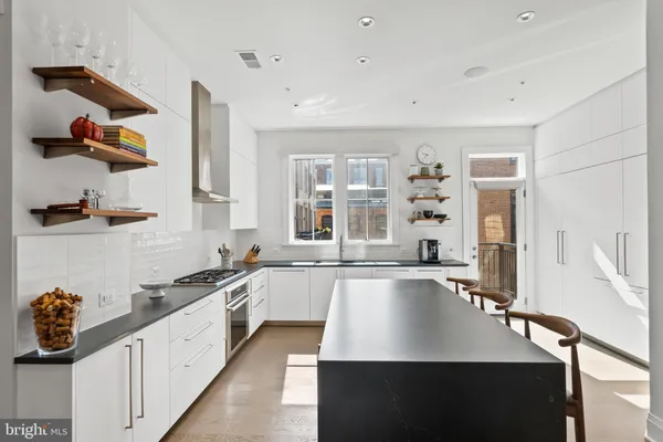 a kitchen with stainless steel appliances granite countertop a stove top oven a sink a dining table and chairs with wooden floor