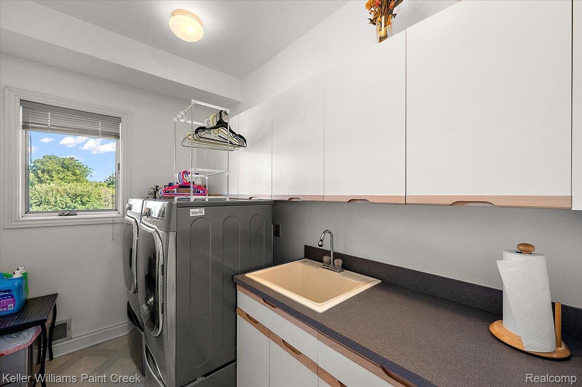 69069 Campground Road Romeo, MI 48065 - Photo 37 of 78 Dedicated laundry area featuring a built-in utility sink with a stainless steel faucet, ample white cabinetry for storage, and durable countertop space