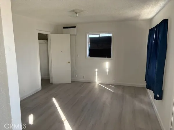a view of an empty room with wooden floor and a cabinet