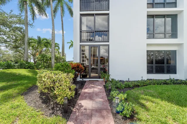 a front view of a multi story residential apartment building with yard and bench