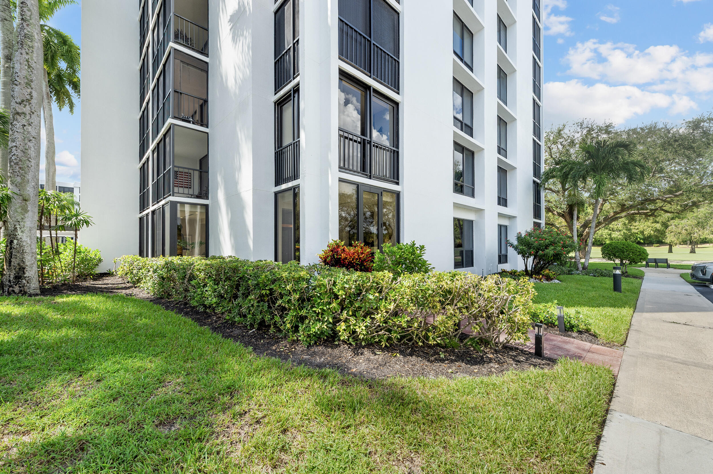 7819 Lakeside Boulevard, Unit 814 Boca Raton, FL 33434 - Photo 24 of 37 a front view of a multi story residential apartment building with yard and bench